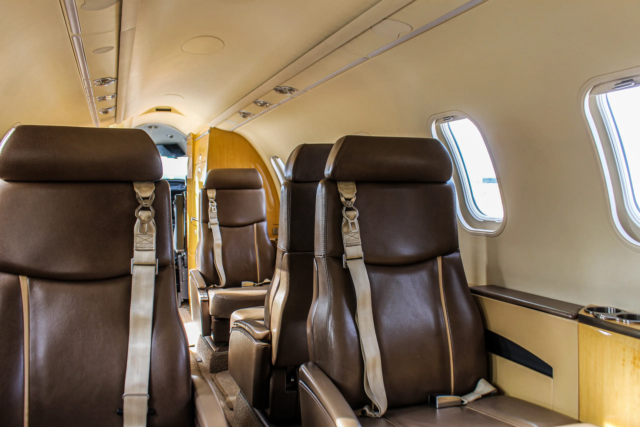 View of the aircraft cabin interior with brown leather seats and windows on the right side.