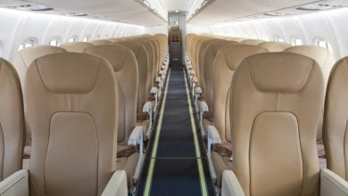 Interior view of an aircraft cabin with rows of tan leather seats.