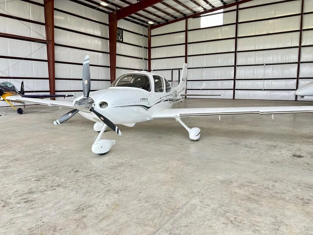 A front view of a white Cirrus SR22 aircraft with registration N248G, parked in a hangar.