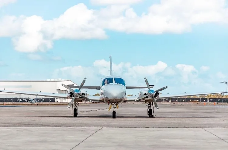 Front view of a twin-engine aircraft on the tarmac.