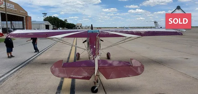 Rear view of a light aircraft on the tarmac with a purple and white paint scheme.