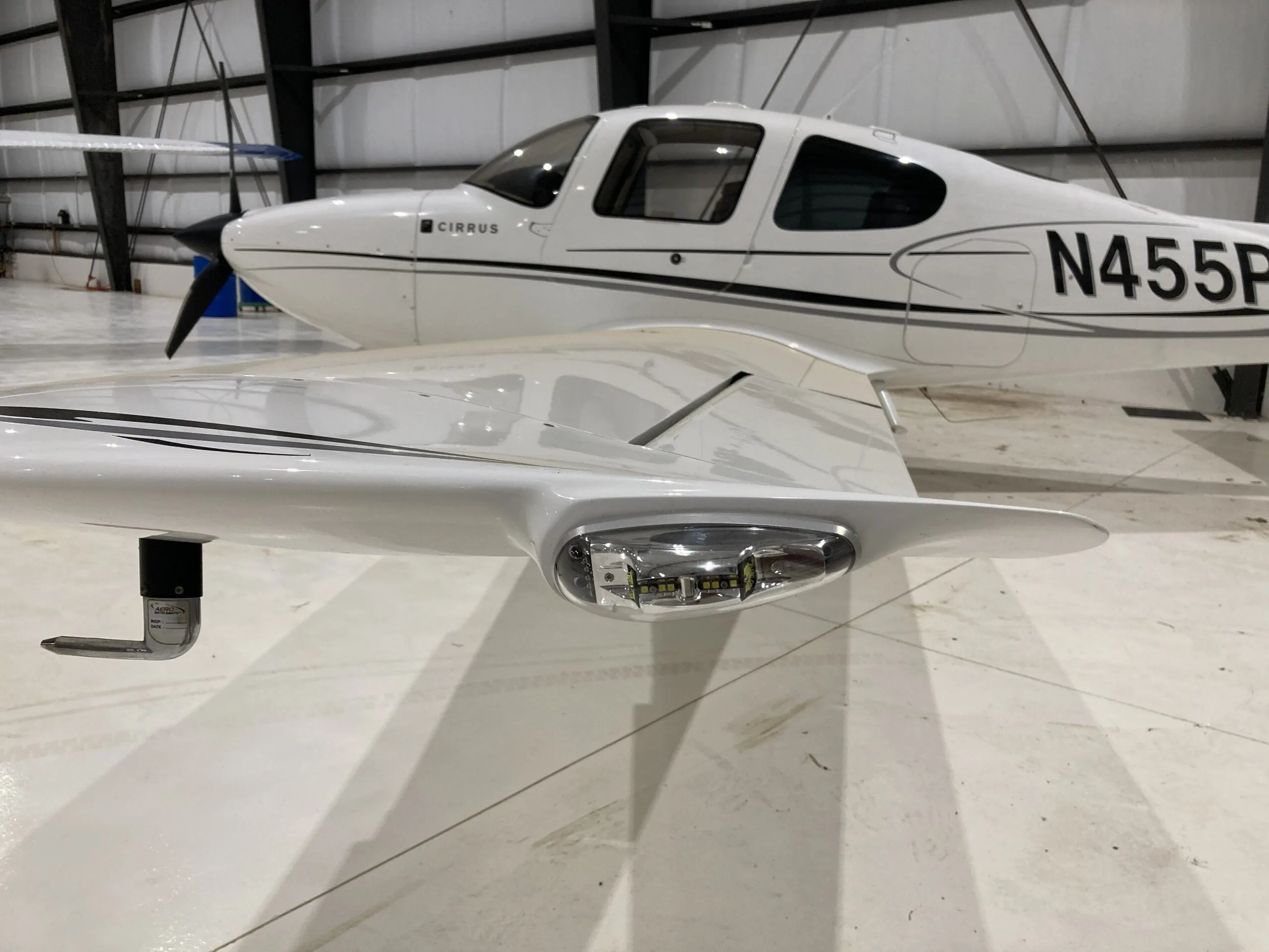 Close-up of the right wingtip of a white Cirrus SR22 aircraft, showing the navigation light.