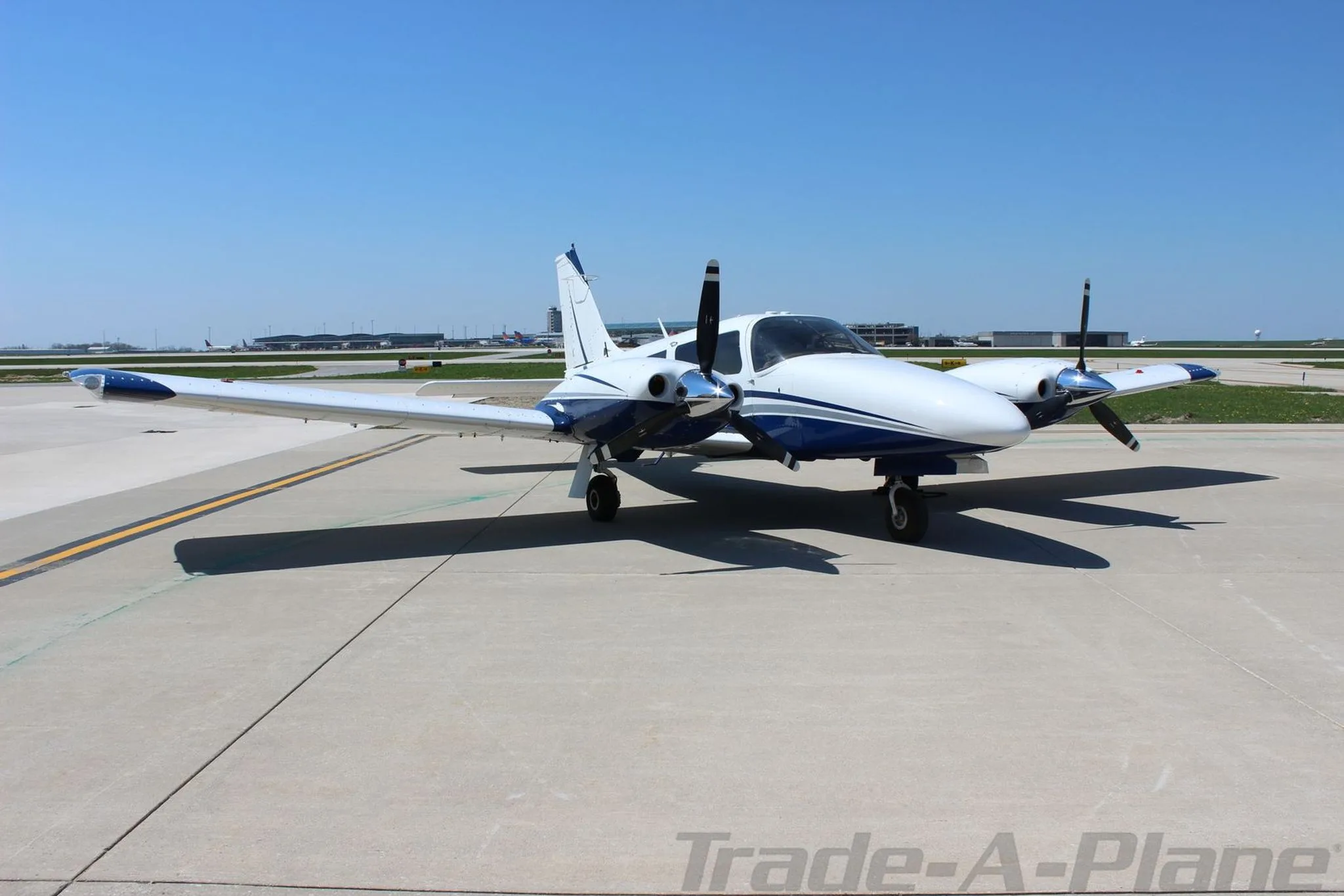 A front-quarter view of the white and blue Piper Seneca aircraft N8186R parked on an airport tarmac.