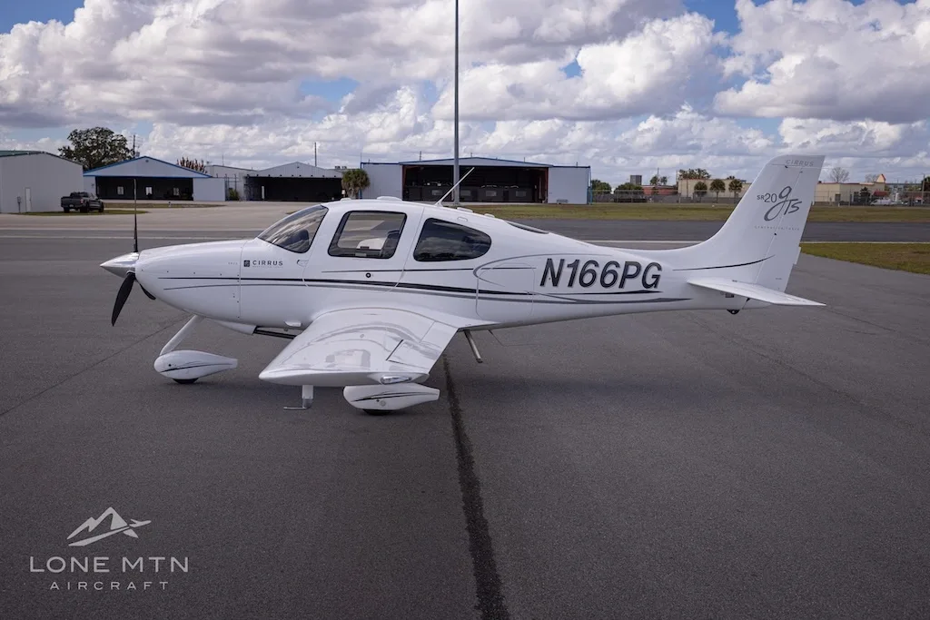 A side view of the white Cirrus SR20 aircraft (N166PG) parked on an airport tarmac.
