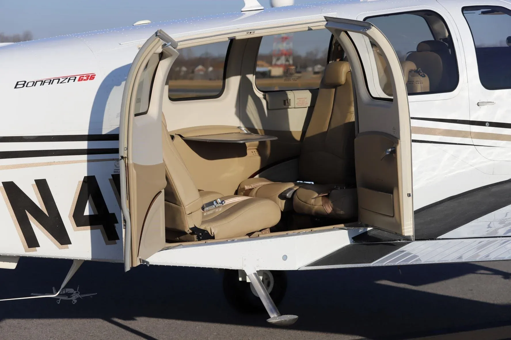 The open cabin door of a Beechcraft Bonanza G36 revealing tan leather seats and interior.