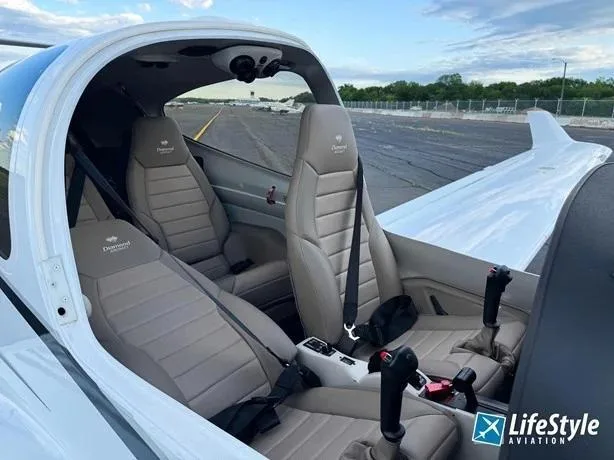 The light tan leather interior of a Diamond DA40 aircraft, showing the front and rear seats and center console controls.