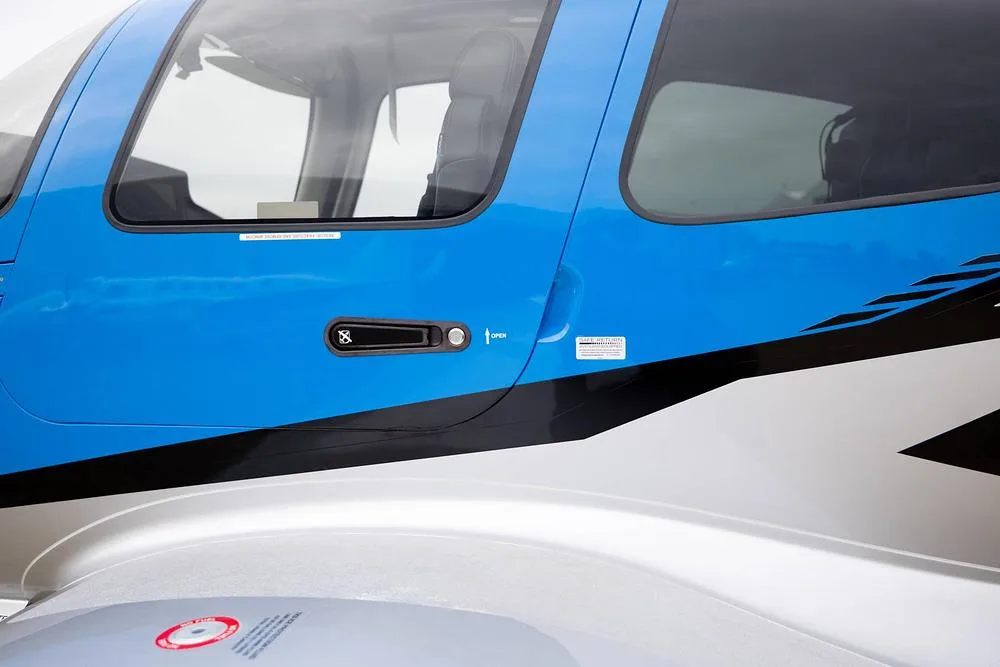 A close-up of the blue and silver side of a Cirrus SR22T GTS, highlighting the passenger door and window.