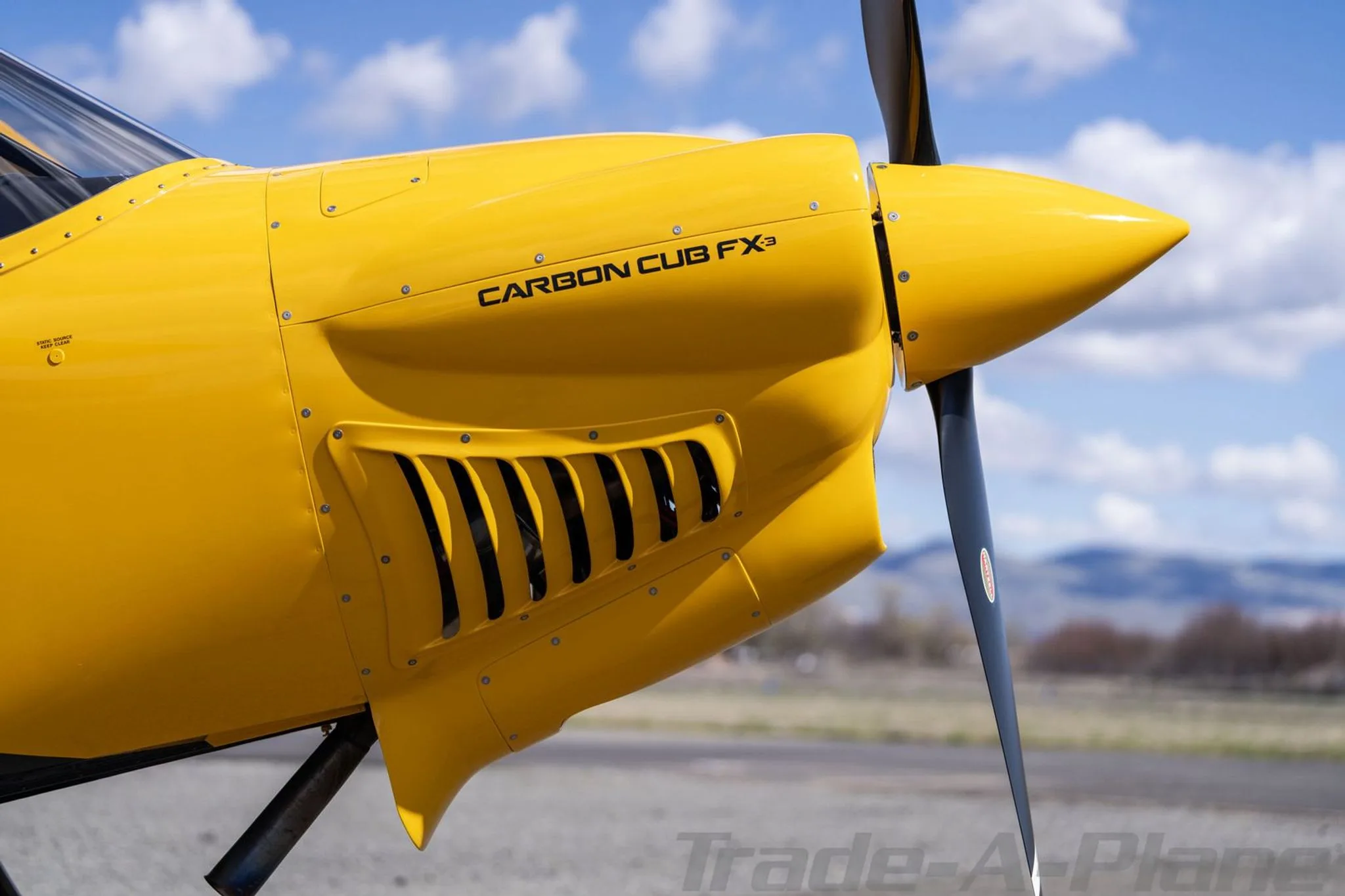 A close-up side view of the yellow engine cowling and propeller of a Carbon Cub FX3.
