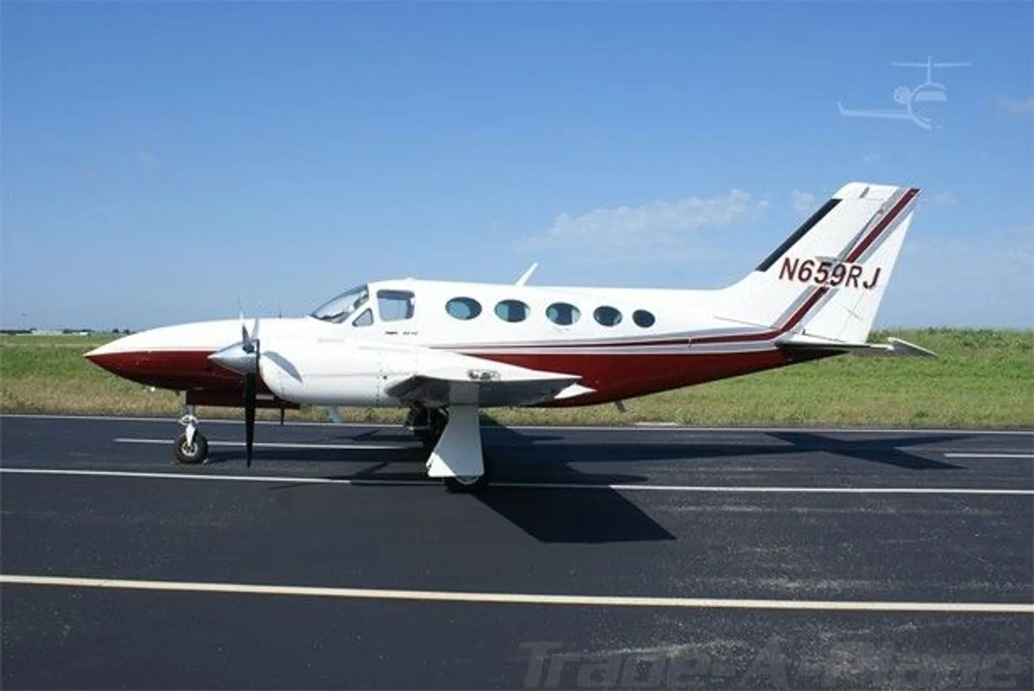A side view of a white and maroon Cessna 421C Golden Eagle aircraft (N659RJ) parked on an asphalt runway under a clear blue sky.