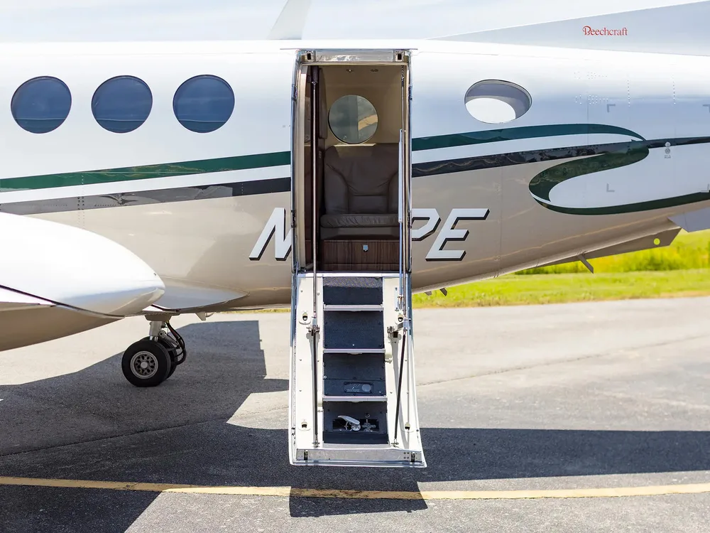 The airstair door of the Beechcraft King Air N29PE is open, revealing the steps and a glimpse of the cabin interior.