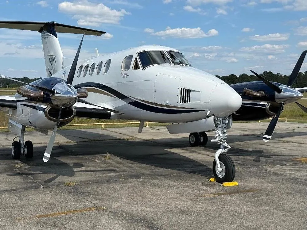 A front view of the white and dark blue Beechcraft King Air N3PX parked on an tarmac.