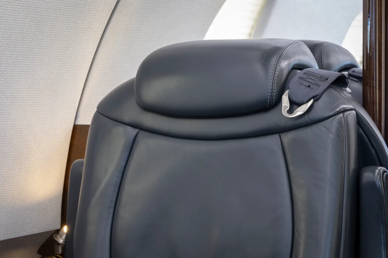 A close-up view of a black leather aircraft seat with a visible seatbelt.