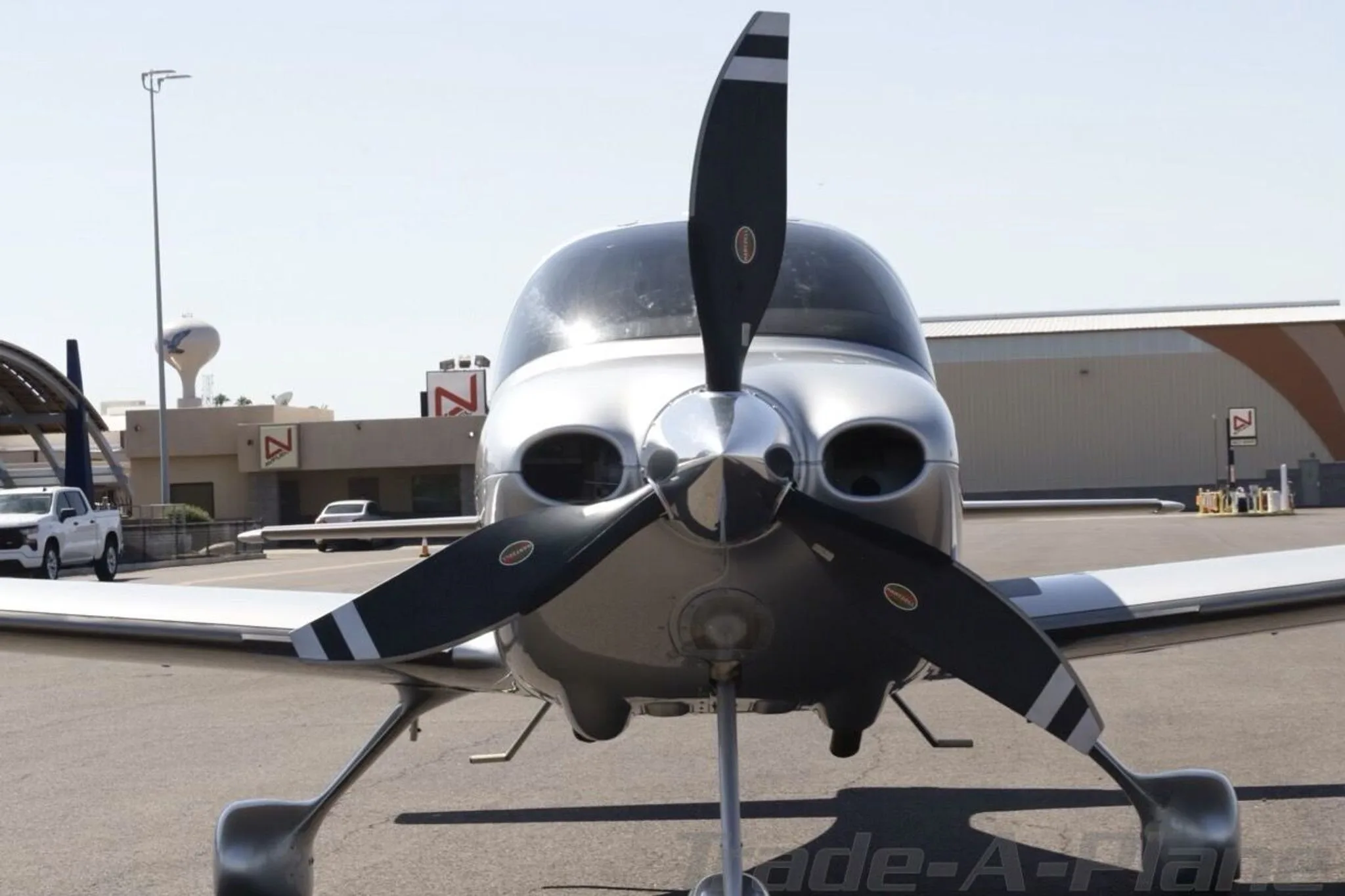 A head-on view of the silver Cirrus SR22 aircraft showing its propeller and nose.