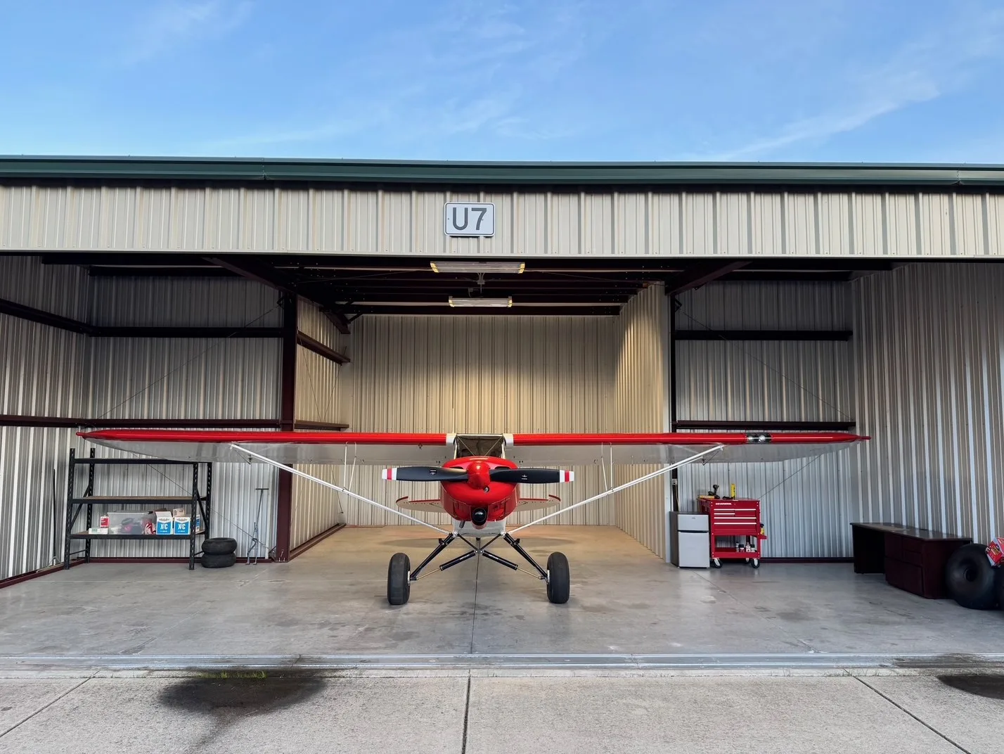 A red and white bush plane, N8287B, seen from the front, parked inside a hangar.