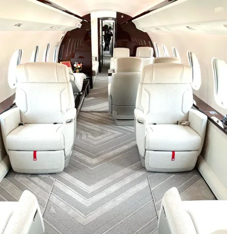 View of the aircraft interior with white leather seats and patterned carpet.