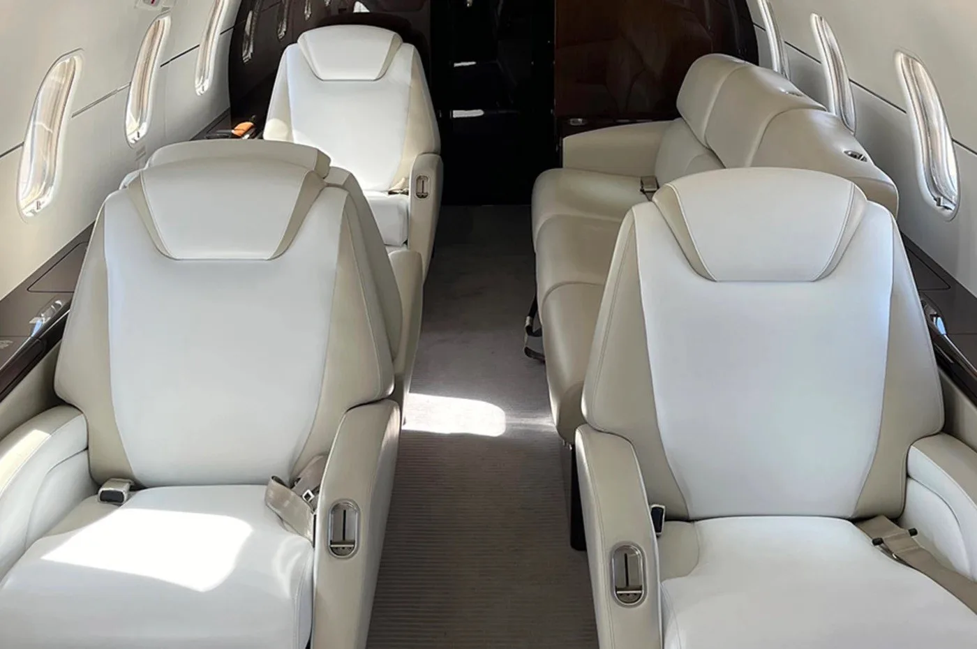 The interior cabin of a business jet, featuring light-colored leather seats arranged in a club configuration.