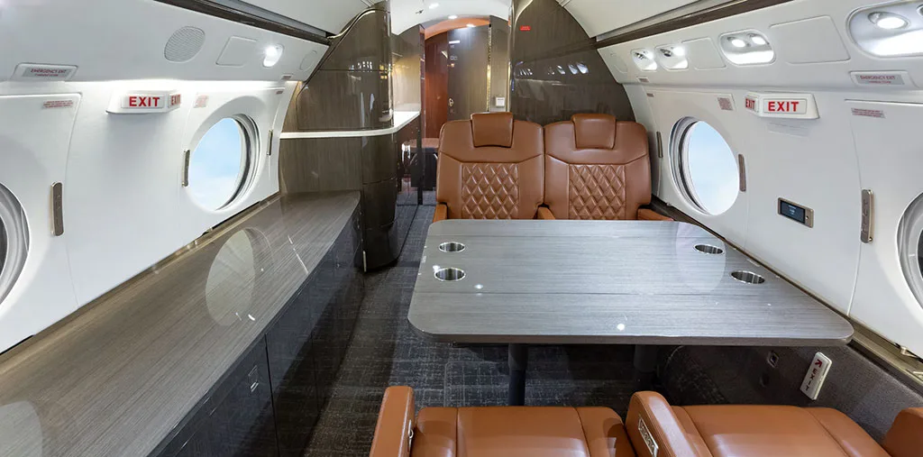 A view inside the aircraft cabin showing a dining or work table with brown leather seats.
