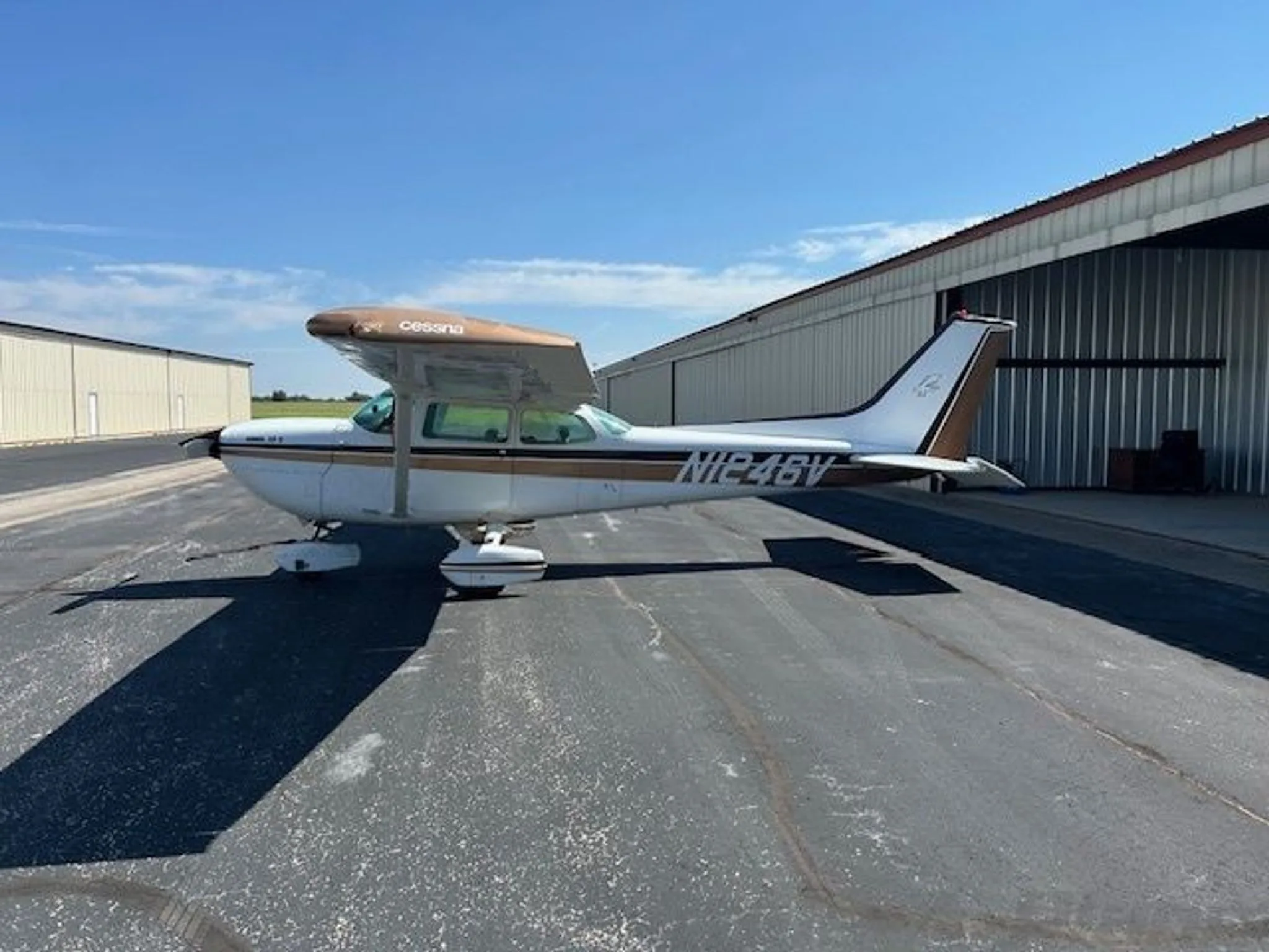 Side view of a white and brown Cessna R172K (N1246V) parked on an asphalt ramp.