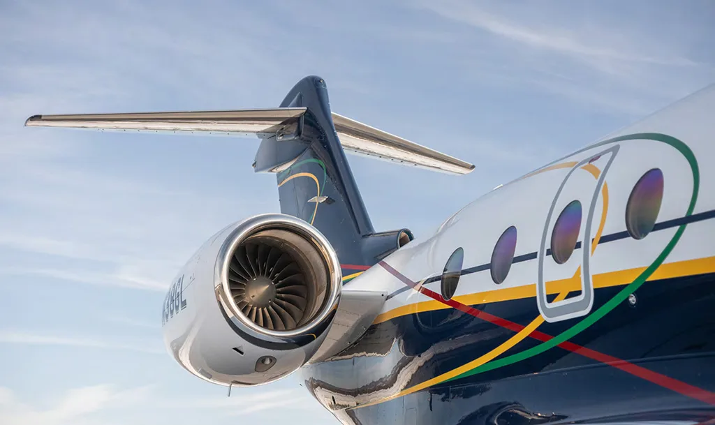 A close-up view of the tail, engine, and colorful stripe details on the fuselage of the Gulfstream G550, registration N38GL.