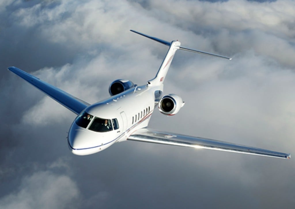 A white private jet flying through the clouds.