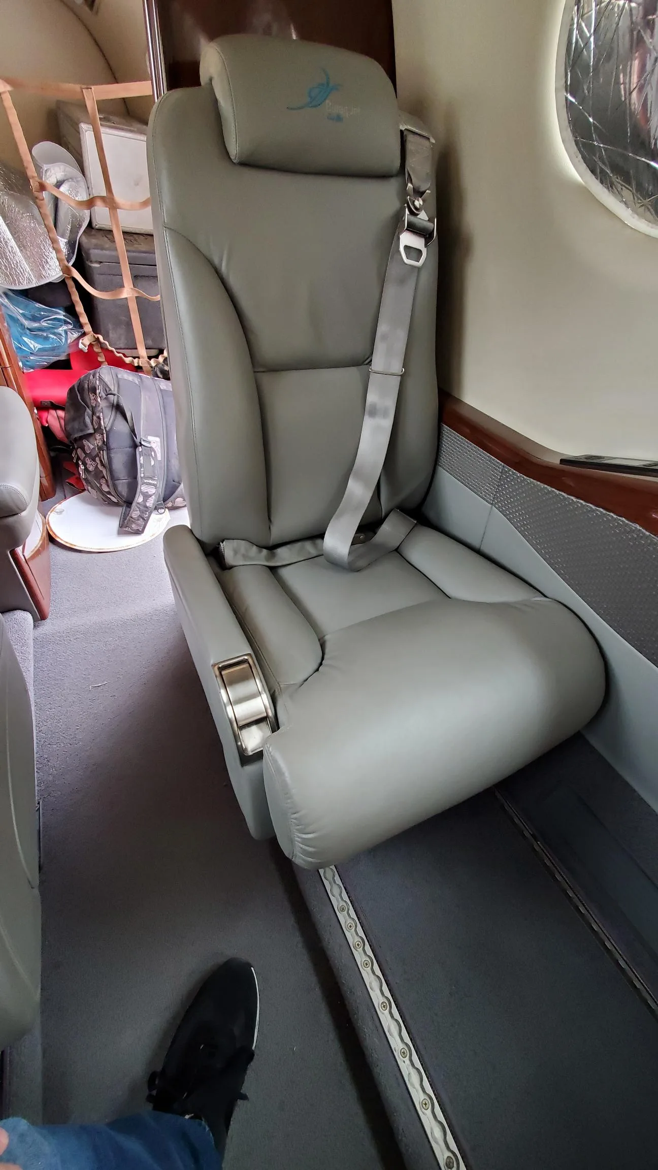Close-up of a cabin seat with a view of luggage and other items.