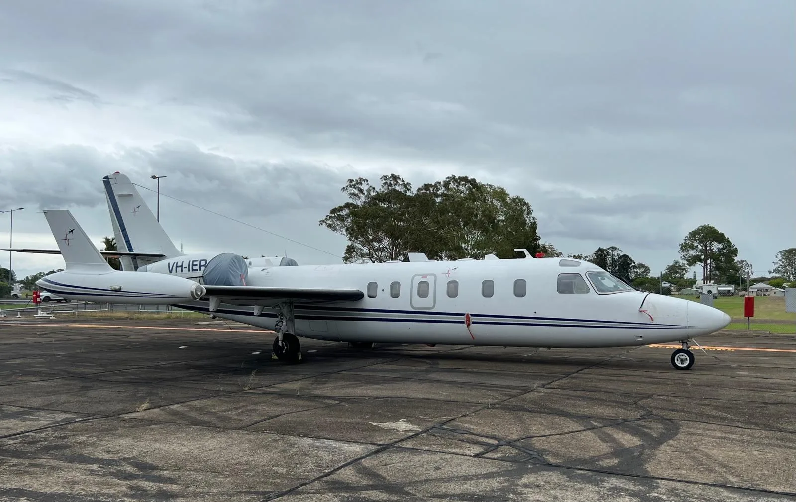 Side view of the VH-IER aircraft on the tarmac under a cloudy sky.