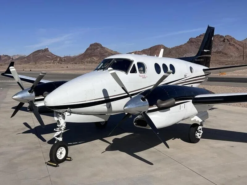 A close-up view of the front-right side of a white and black turboprop aircraft on an airfield.