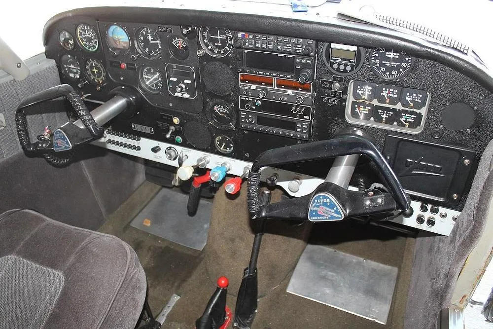The instrument panel and dual yokes of an aircraft cockpit, showing various gauges and radios.