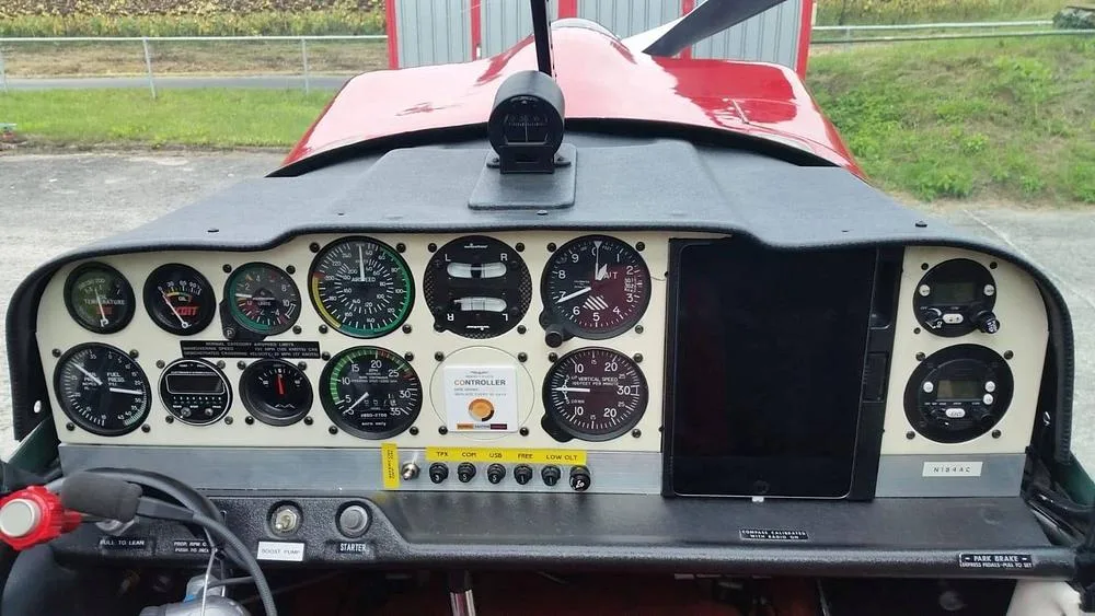 The cockpit instrument panel of the N184AC aircraft, featuring analog gauges and a tablet mount.