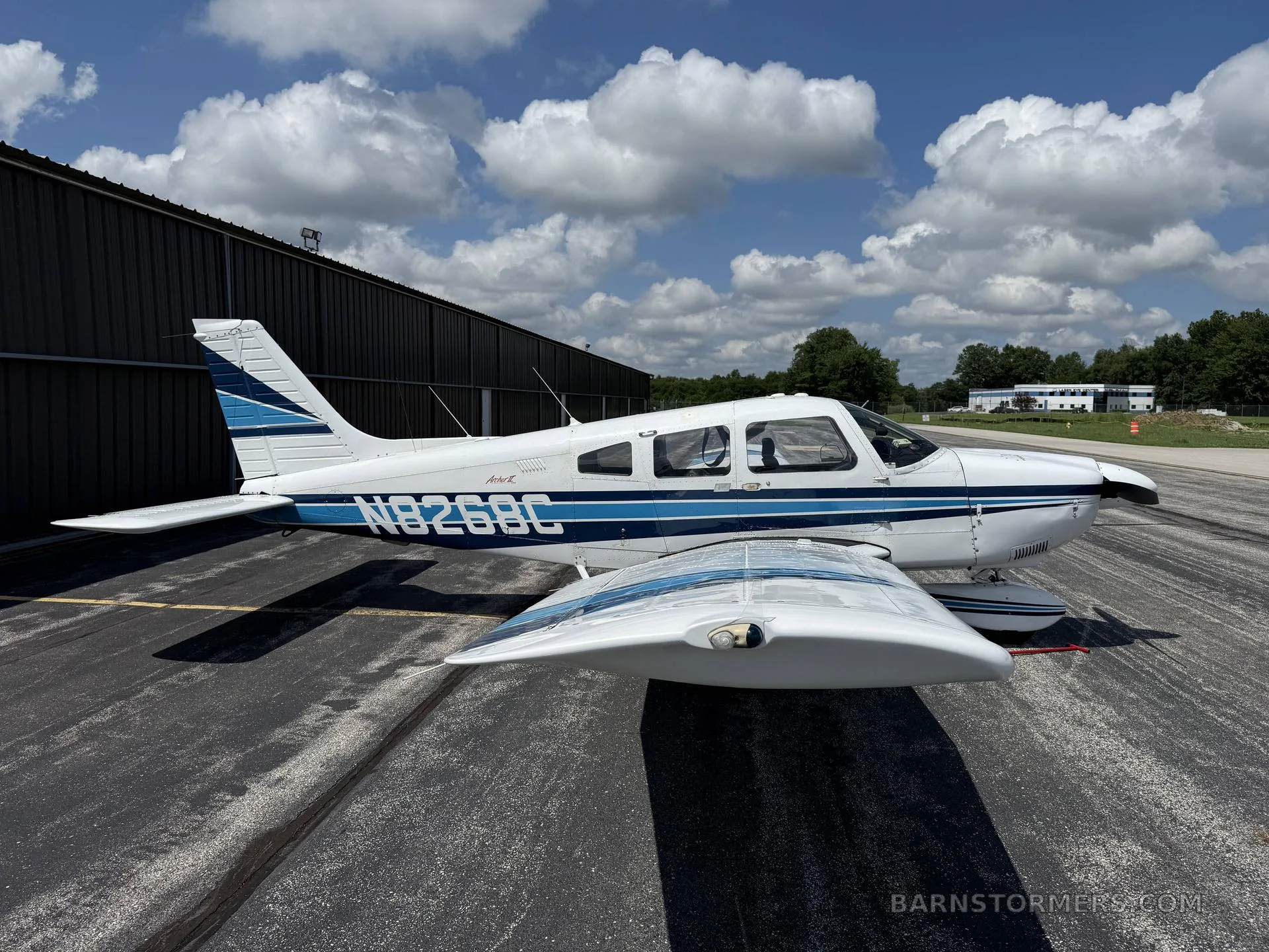 A detailed view of a Piper aircraft cockpit with analog gauges and modern avionics under a blue sky.