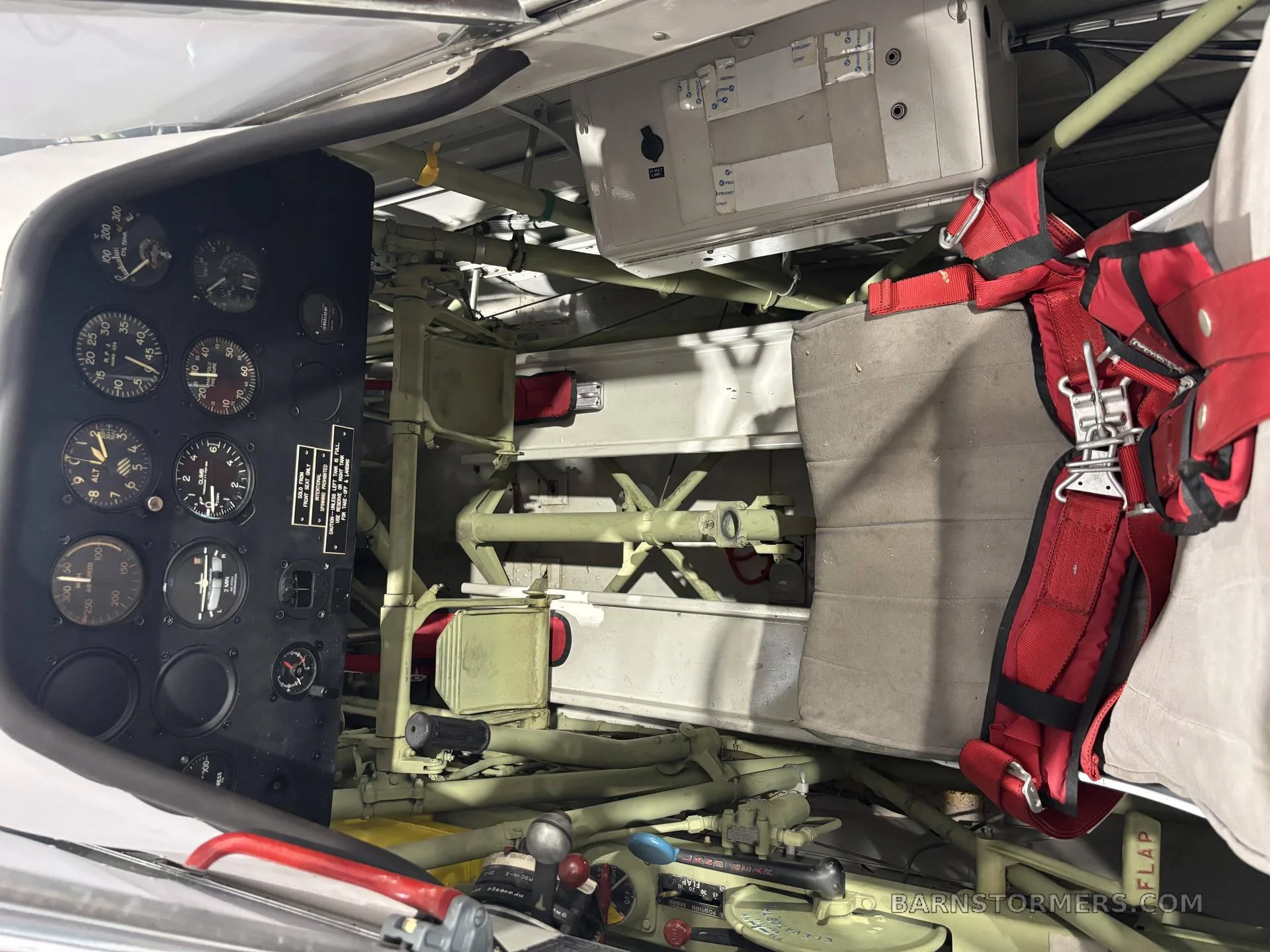 The interior of a T-6G Texan aircraft, showing the rear cockpit area with red harnesses and internal structural elements.