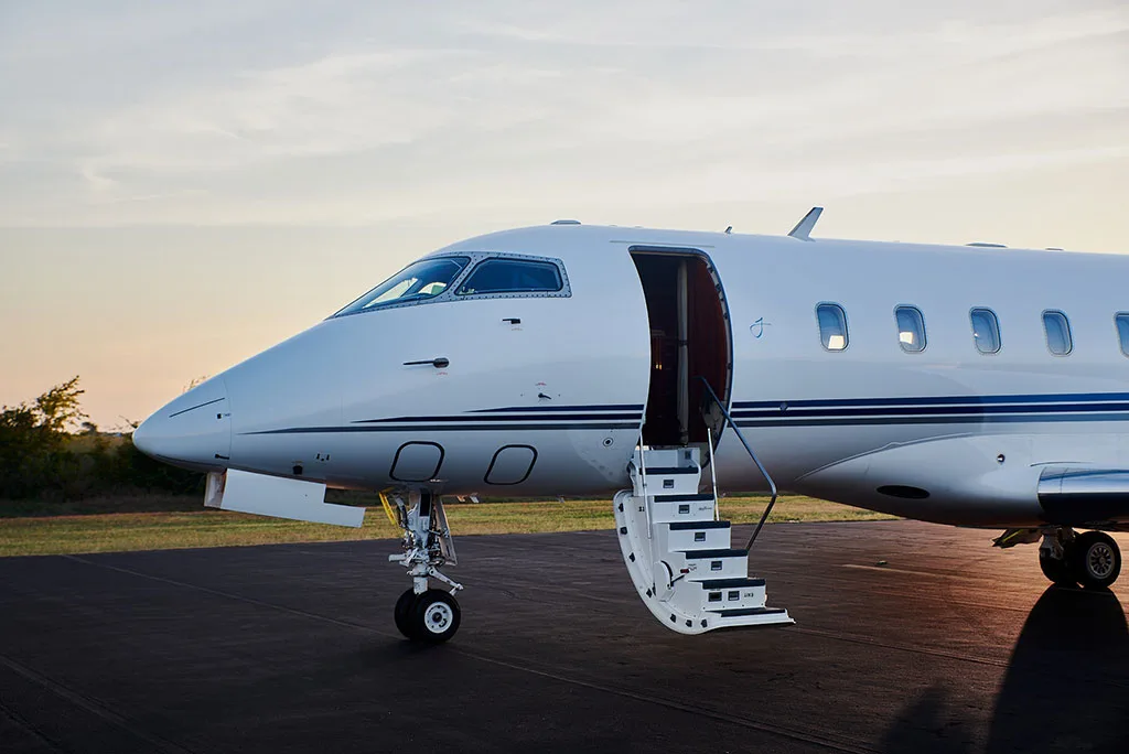 A close-up view of the front fuselage of a white private jet with its entry door and stairs extended.