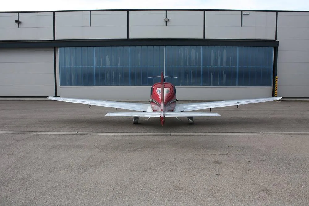 A rear view of a red and white Cirrus SR22 aircraft, registration N722MT, parked on an asphalt apron.