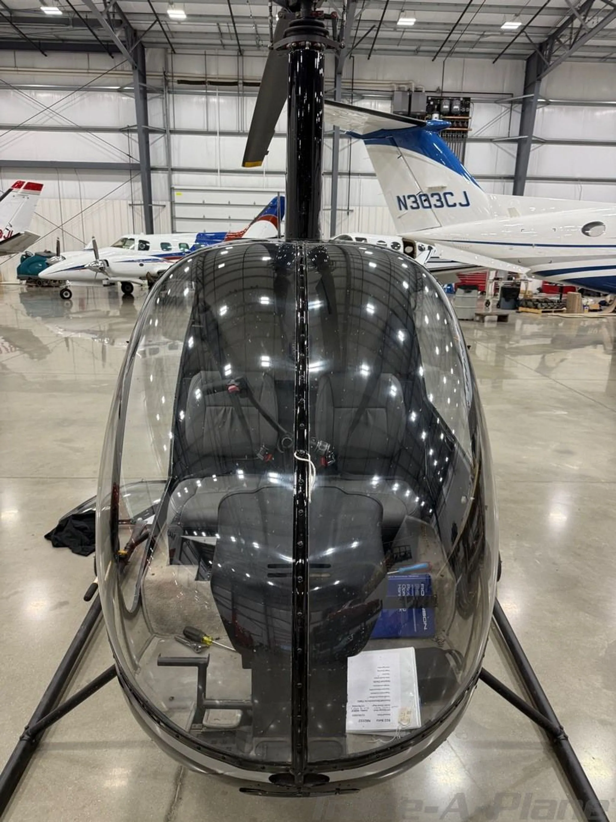 A head-on view of the black Robinson R22 Beta helicopter, N82222, parked in a hangar.