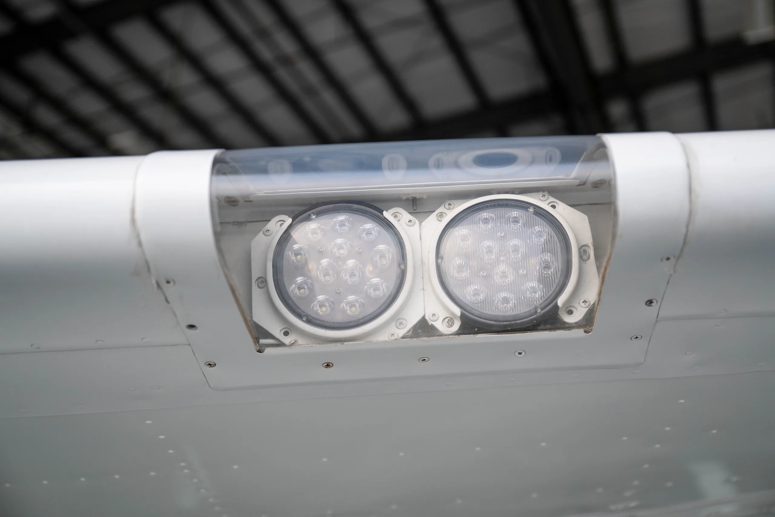 A close-up view of two LED landing lights on the wing of a white aircraft.