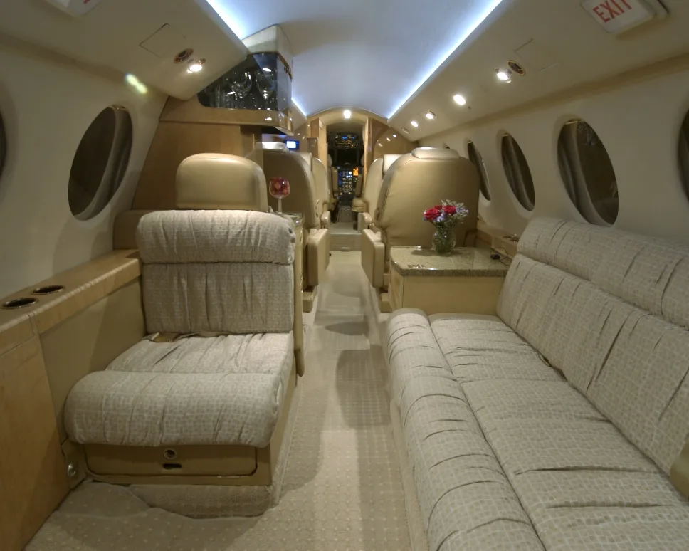 View of the aircraft's interior cabin with seats and a couch.