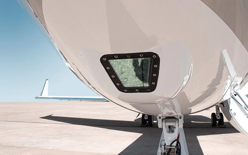 A luxurious aircraft interior with beige leather seats and a polished wooden table extended from the sidewall.