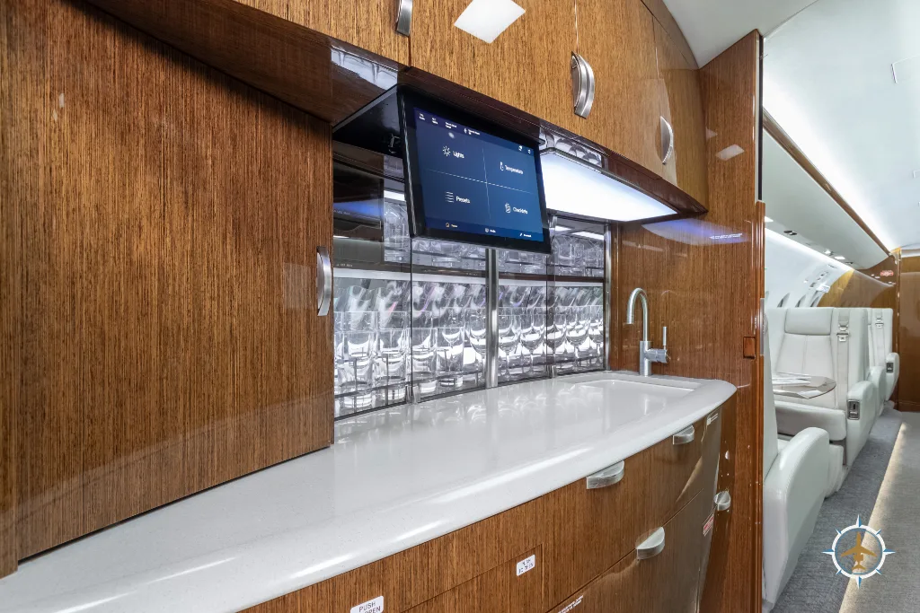 The aircraft galley with a white countertop, sink, glass storage, and a control tablet.