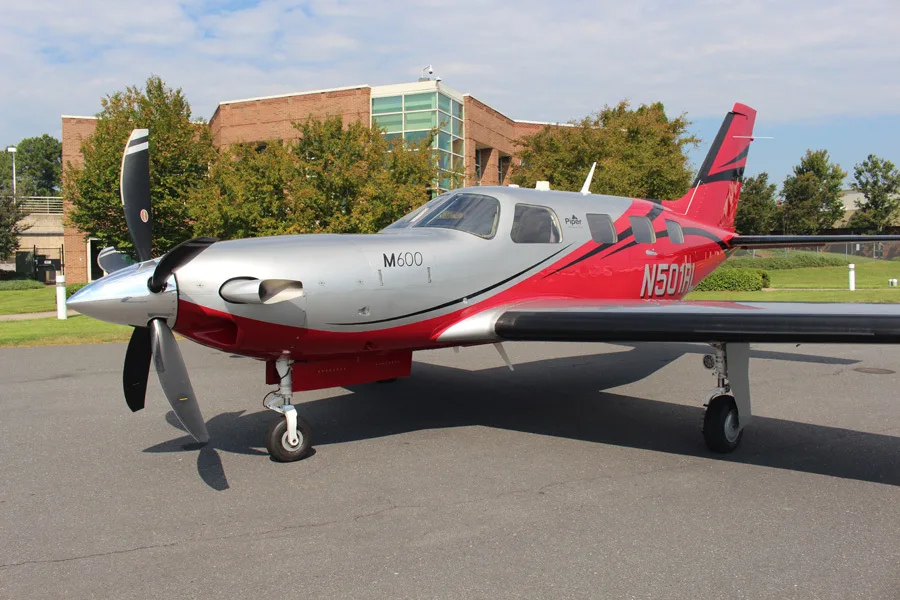 A front-side view of a Piper M600 aircraft, registration N501RL, in a red and silver paint scheme, parked on a tarmac.