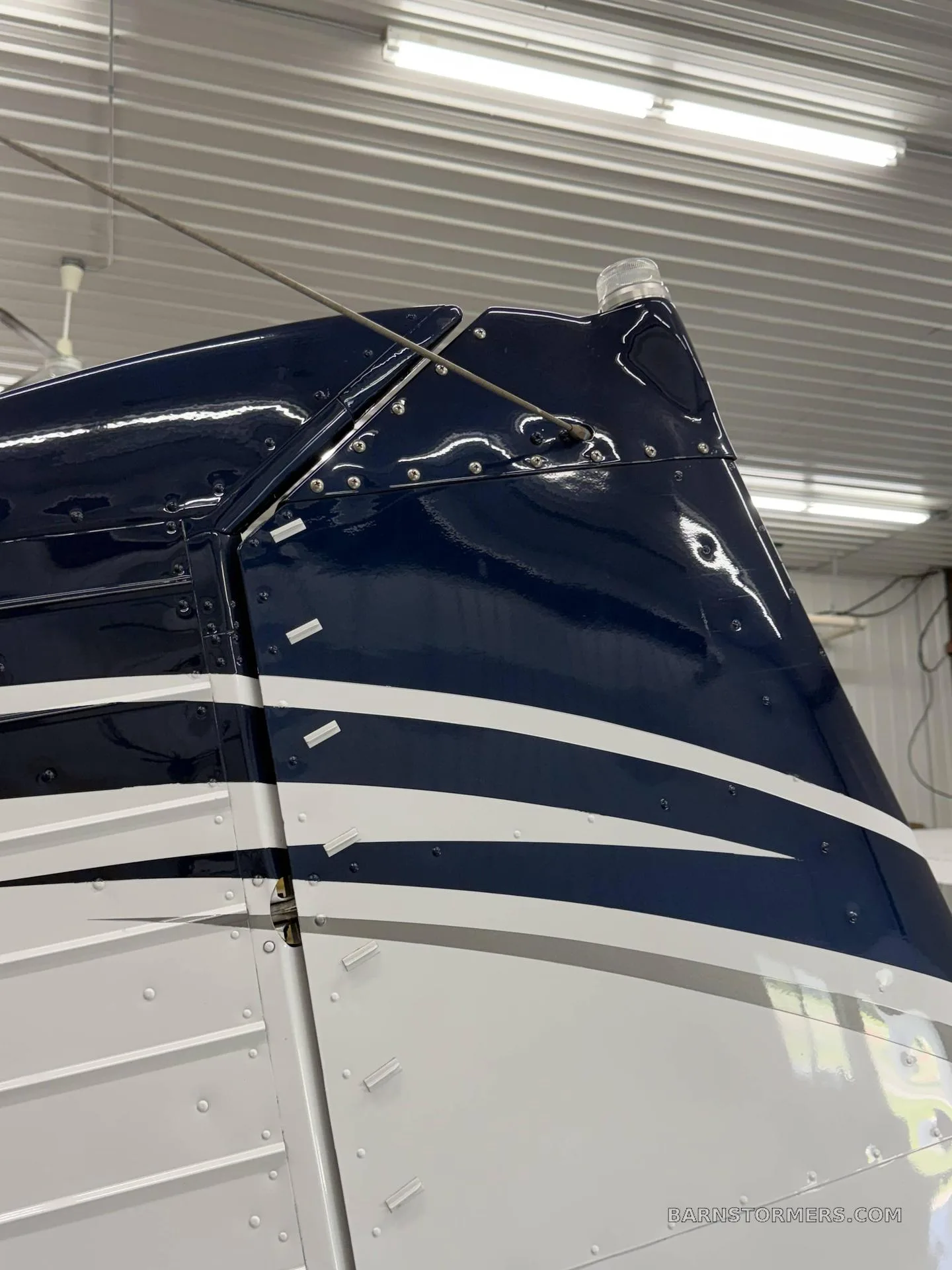 A close-up view of the dark blue and white striped tail section of an aircraft inside a hangar.