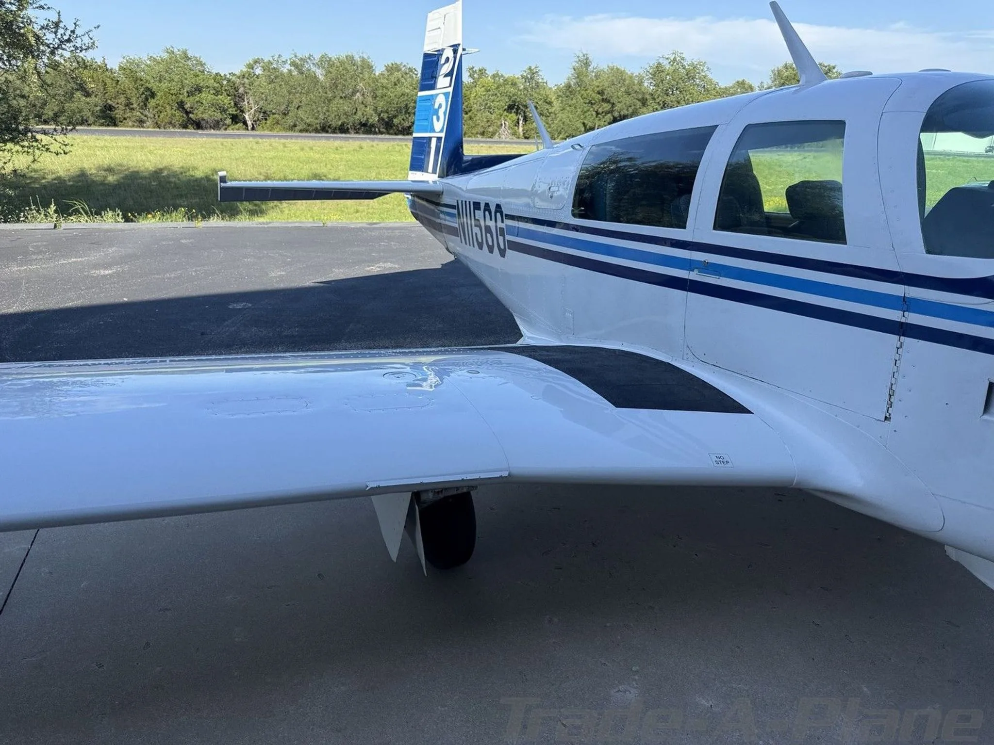 A rear-side view of the white and blue aircraft, N1156G, showing the tail number and wing.