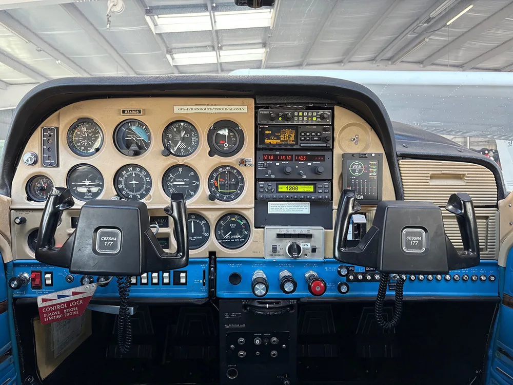 The cockpit of a Cessna 177 aircraft, showing the instrument panel with analog gauges and two "CESSNA 177" labeled yokes.