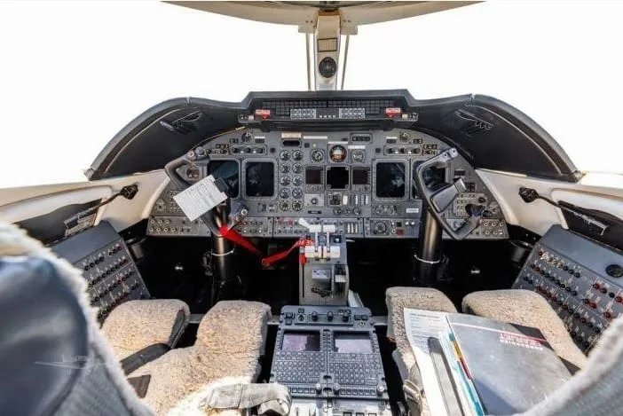 The cockpit of a private jet with a detailed instrument panel and controls.