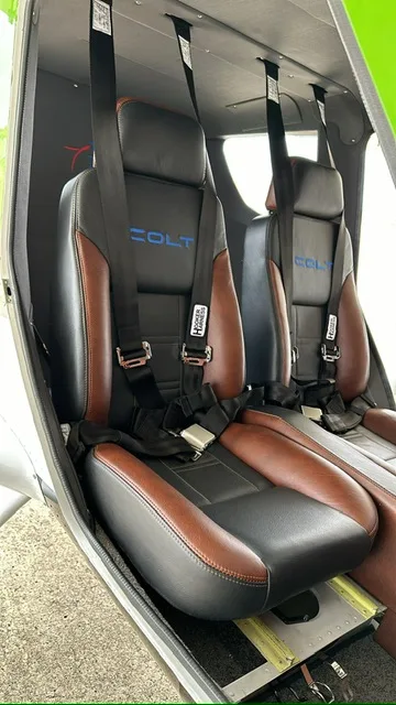 A close-up view of the two-tone brown and black leather seats with 'COLT' embroidered, inside the aircraft cabin.