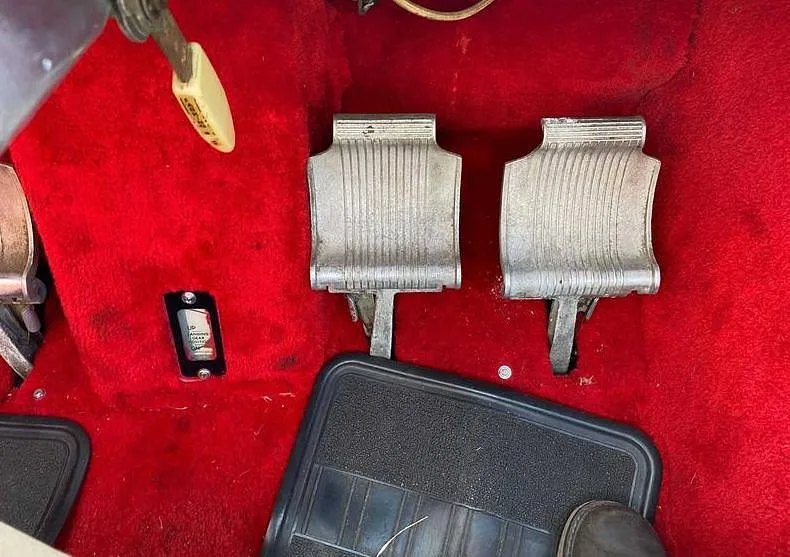 A close-up view of the aircraft's rudder pedals and red carpeted floor in the cockpit area.