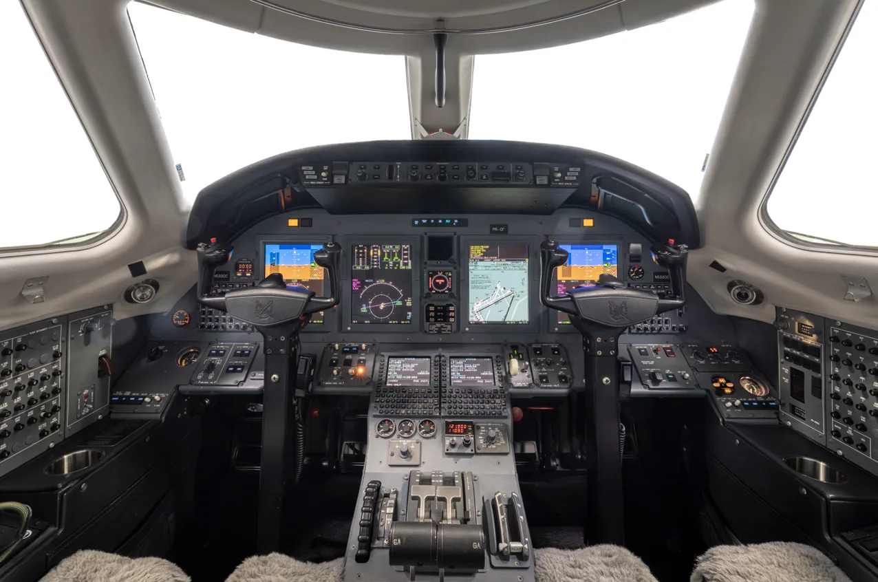 The cockpit of a Cessna Citation jet, featuring multiple digital displays and a complex instrument panel.