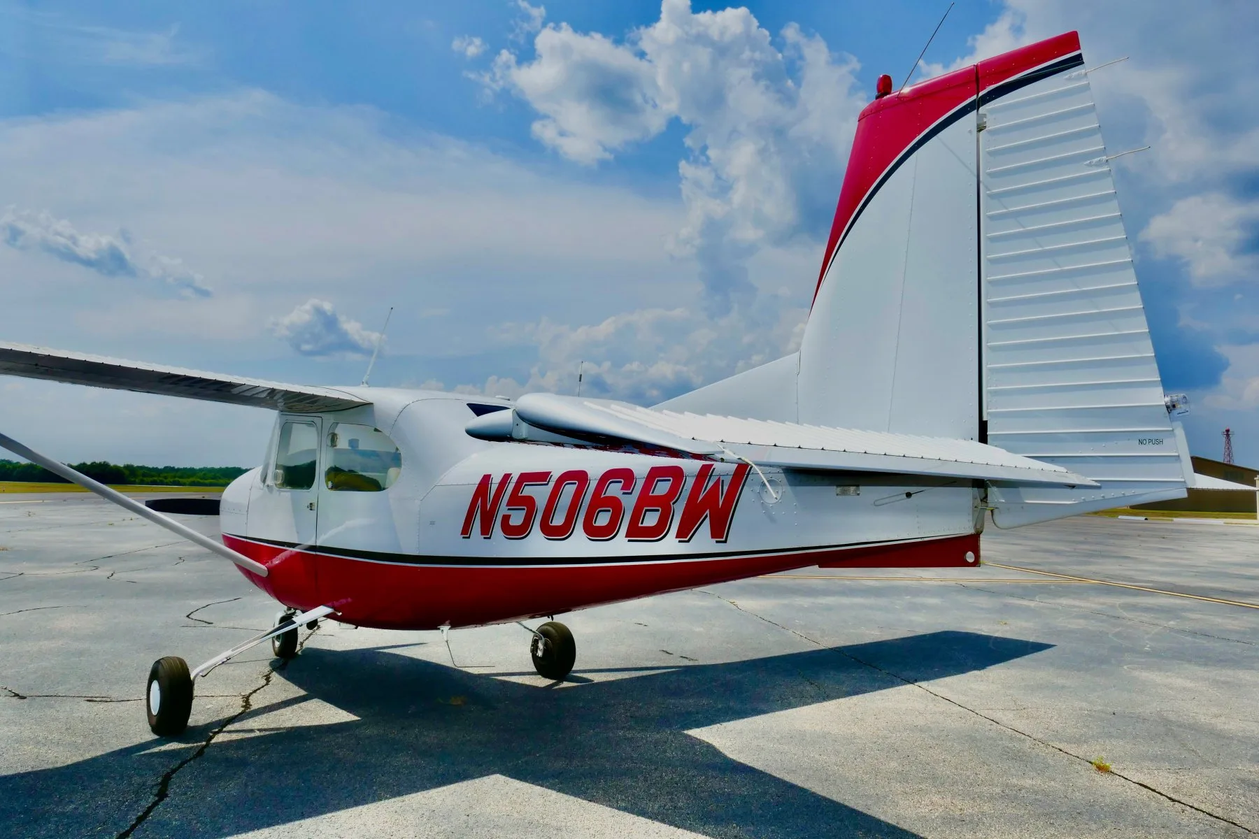 A rear-right view of a white and red Cessna 172 aircraft, N506BW, with a clear view of the tail and registration.