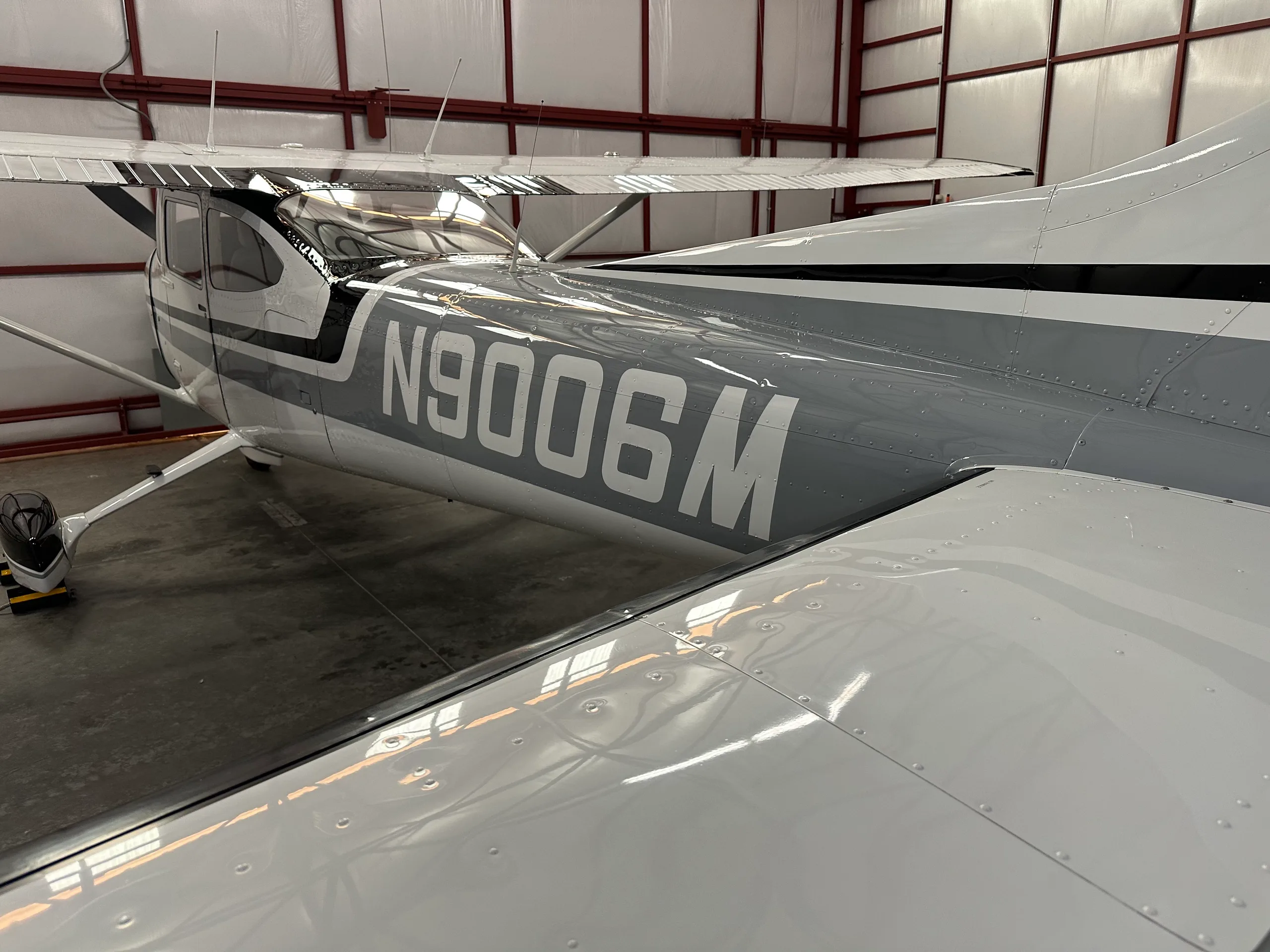 A close-up view of the tail section and wing of the Cessna 182, showing the N9006M registration inside a hangar.