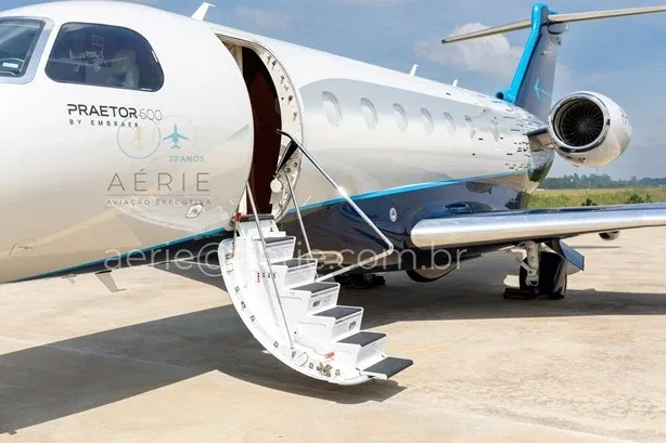 A close-up view of the front of an Embraer Praetor 600 with its main cabin door open and airstairs extended.