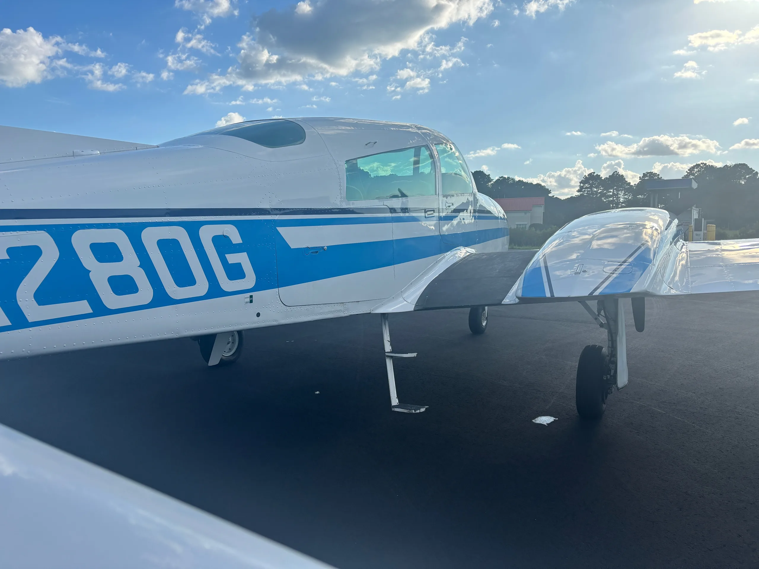 A close-up side view of the white twin-engine aircraft with blue stripes, showing the registration N1280G.